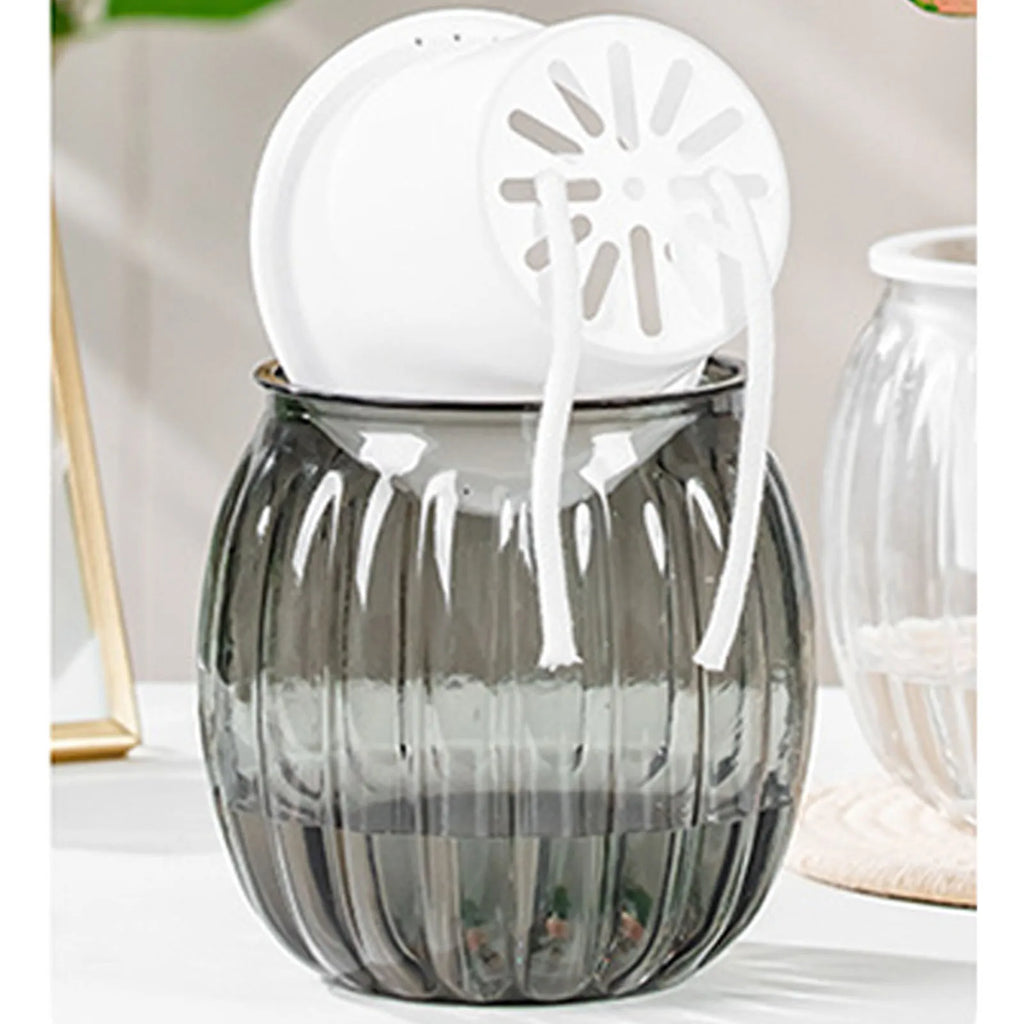 A modern, fluted gray glass self-watering planter with a white inner pot and cotton wicks resting on top.
