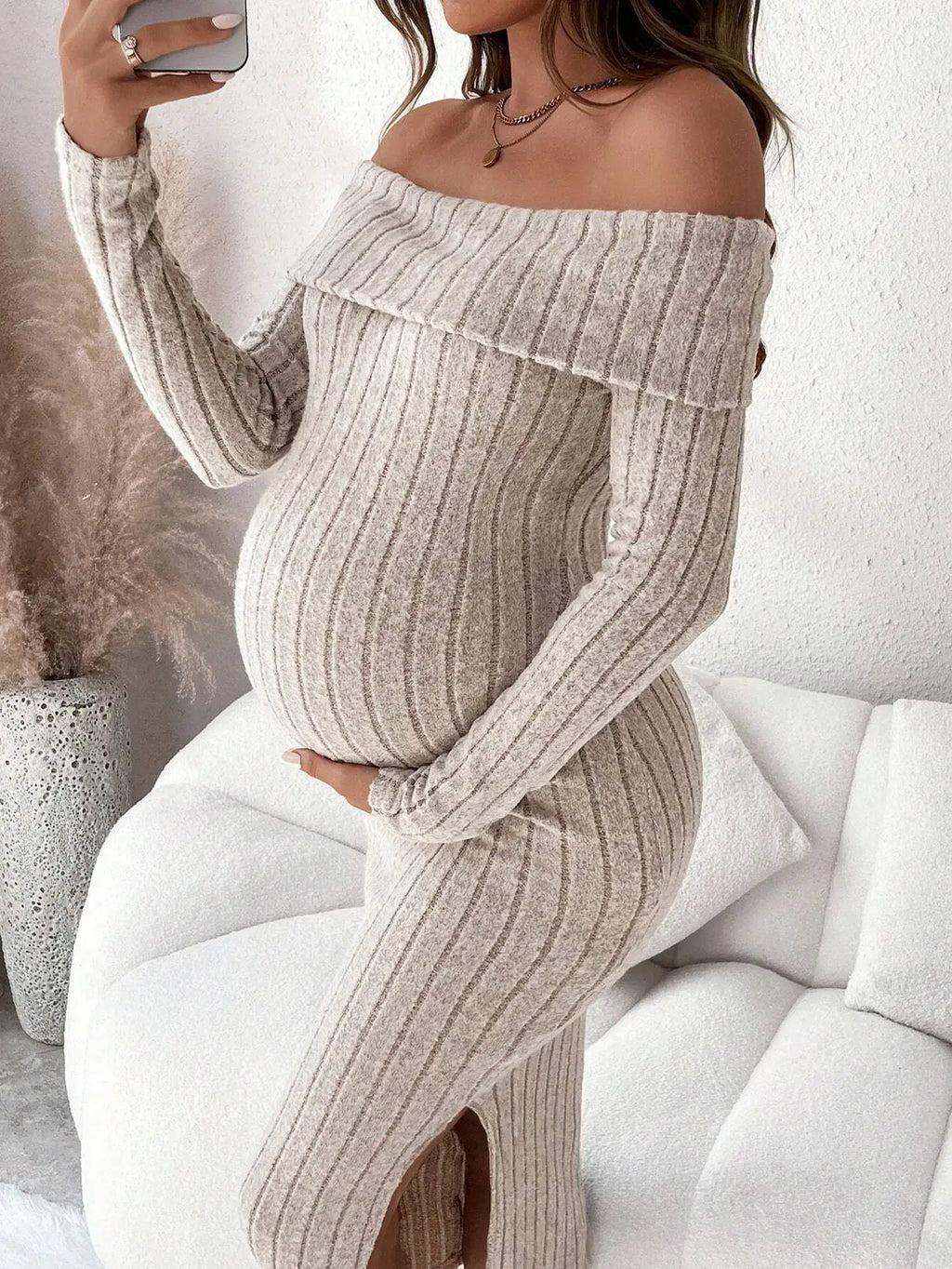 Beige off-the-shoulder maternity ribbed knit dress with long sleeves and a side slit.