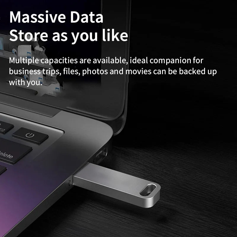 A sleek, silver metal USB flash drive plugged into the side of a laptop.