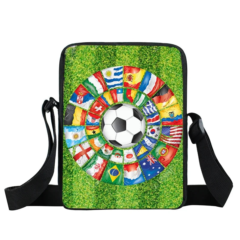 Crossbody bag with a soccer ball and international flags graphic on a green grass background, with black straps.