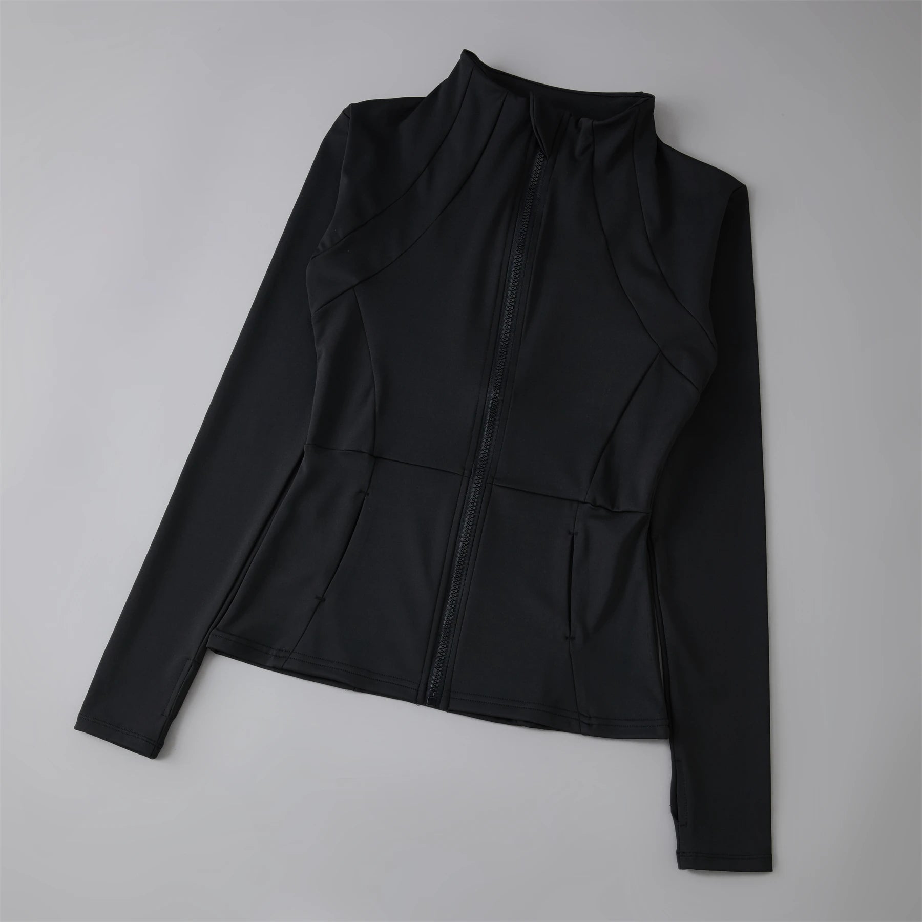 Women’s black fitted athletic jacket with a high collar, full-length zip, long sleeves, and paneled seam detailing.