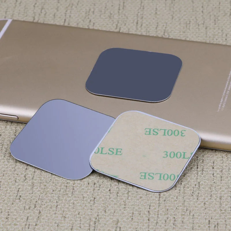 Three thin, square metal plates with rounded corners and adhesive backing, displayed on a gold smartphone surface.