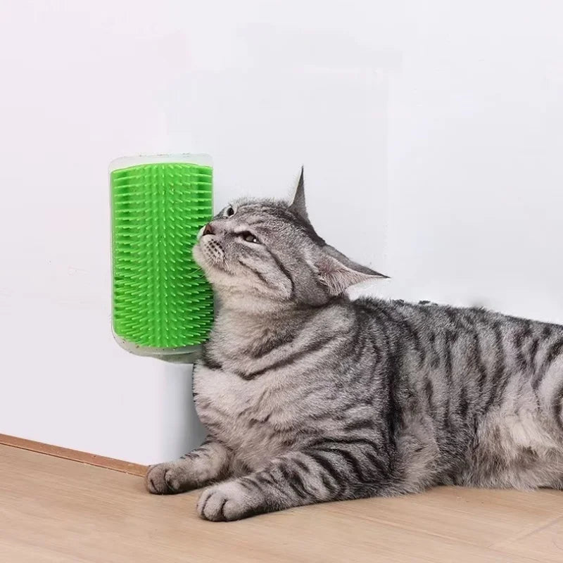 A tabby cat rubs its face against a bright green wall-mounted silicone cat self-groomer brush.