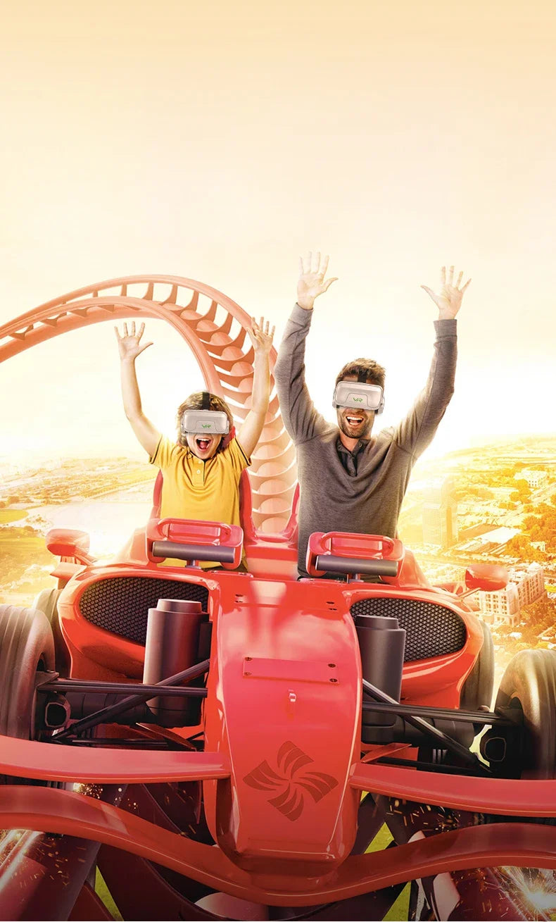 An adult and child wearing grey VR headsets on a virtual red racing car ride, cheering with arms raised.