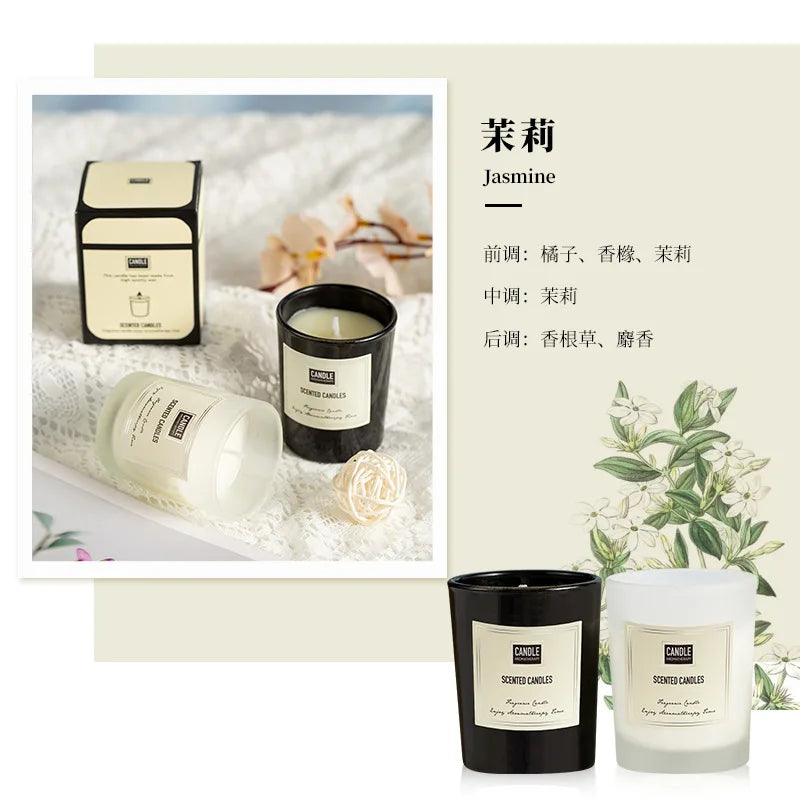 A pair of jasmine-scented candles in black and frosted white glass jars with minimalist labels, set on lace fabric.