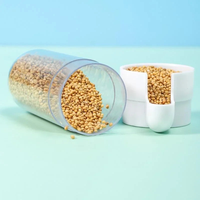 Clear plastic cylindrical food dispenser with a white cap, filled with small beige grains, on a light blue background.