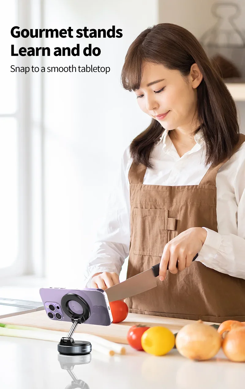 A black, adjustable magnetic phone stand supporting a purple smartphone on a kitchen counter while a woman chops food.