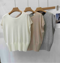 Three lightweight, short-sleeved knitted sweater vests in white, beige, and grey with a ribbed hem on wooden hangers.