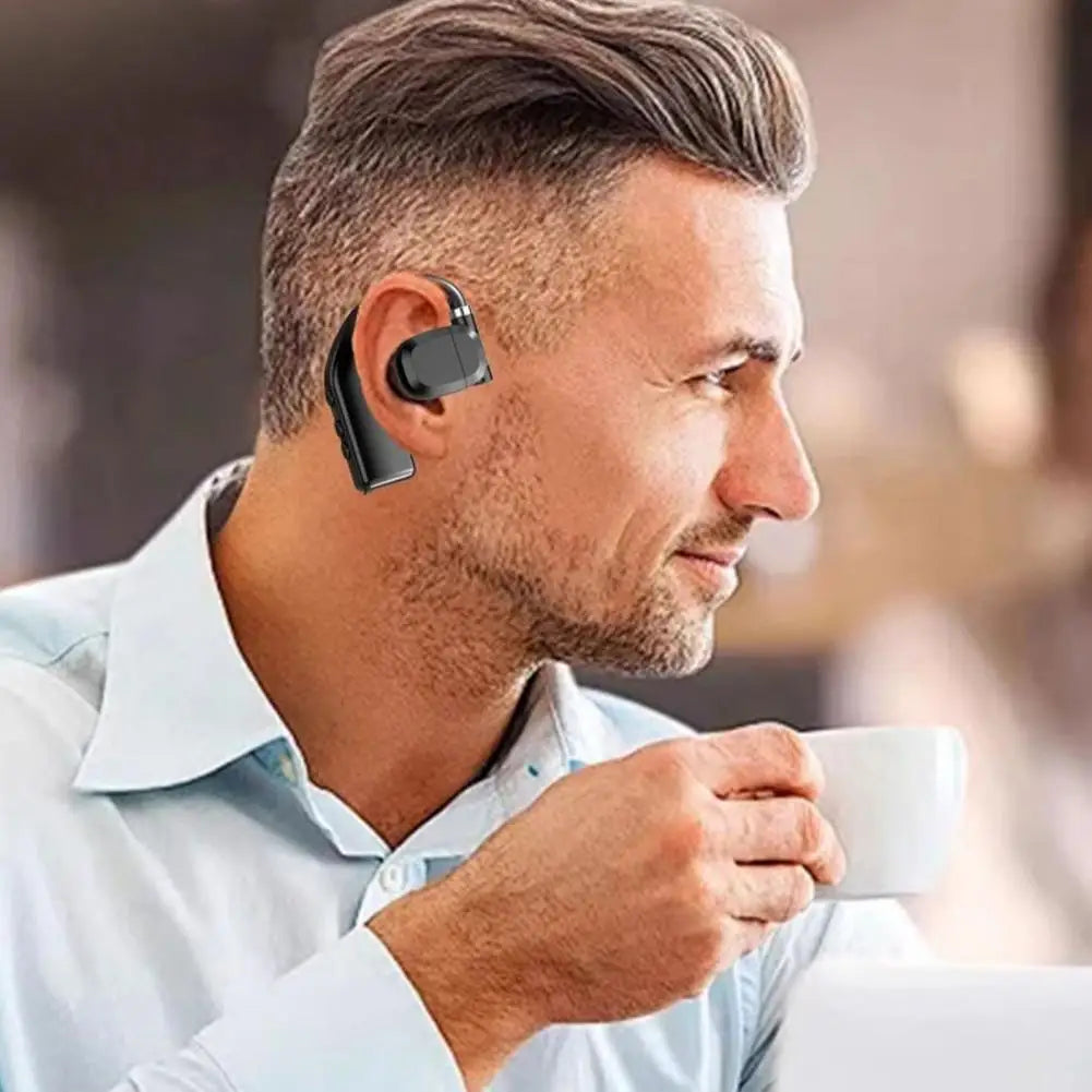 A man wearing a sleek, black over-ear Bluetooth headset while holding a white coffee cup.