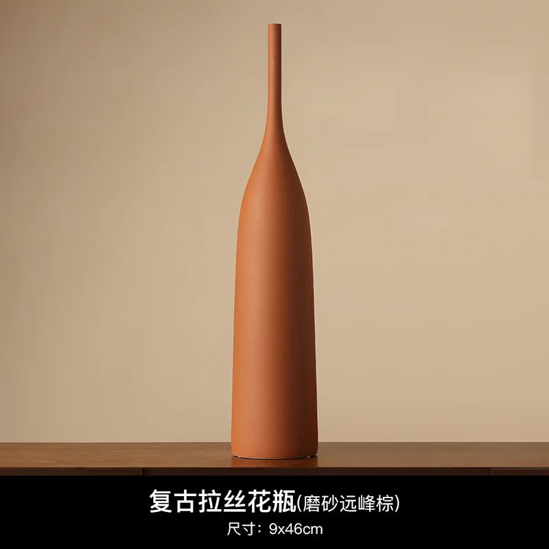 Tall, slender terracotta ceramic vase with a minimalist Wabi-Sabi aesthetic and a matte, earthy brown finish.