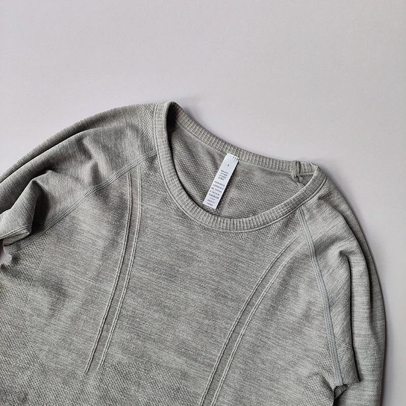 Grey long-sleeve seamless activewear top with a round neck and textured, breathable mesh detail panels.
