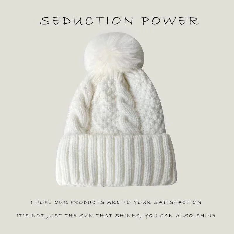 White cable-knit winter beanie hat with a fluffy matching pom-pom and a thick ribbed turn-up cuff.