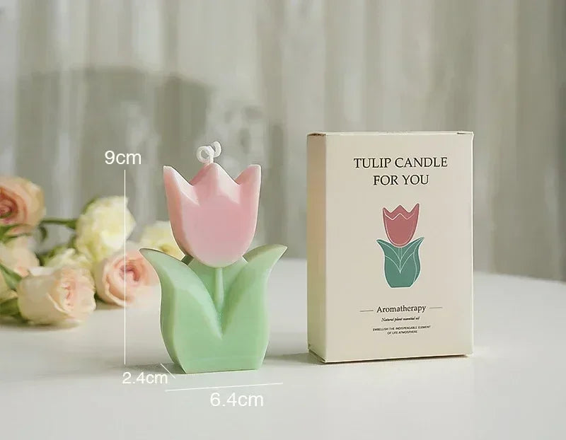 A pink and green tulip-shaped aromatherapy candle next to its cream-coloured presentation box.