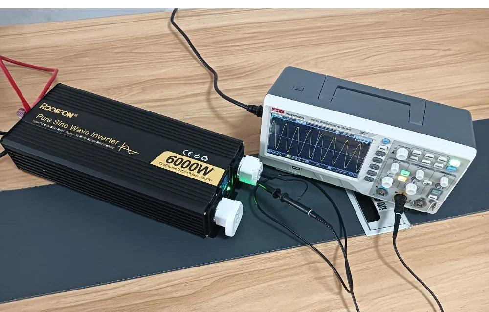 Black 6000W pure sine wave inverter connected to an oscilloscope on a wooden desk, displaying a clean wave output.