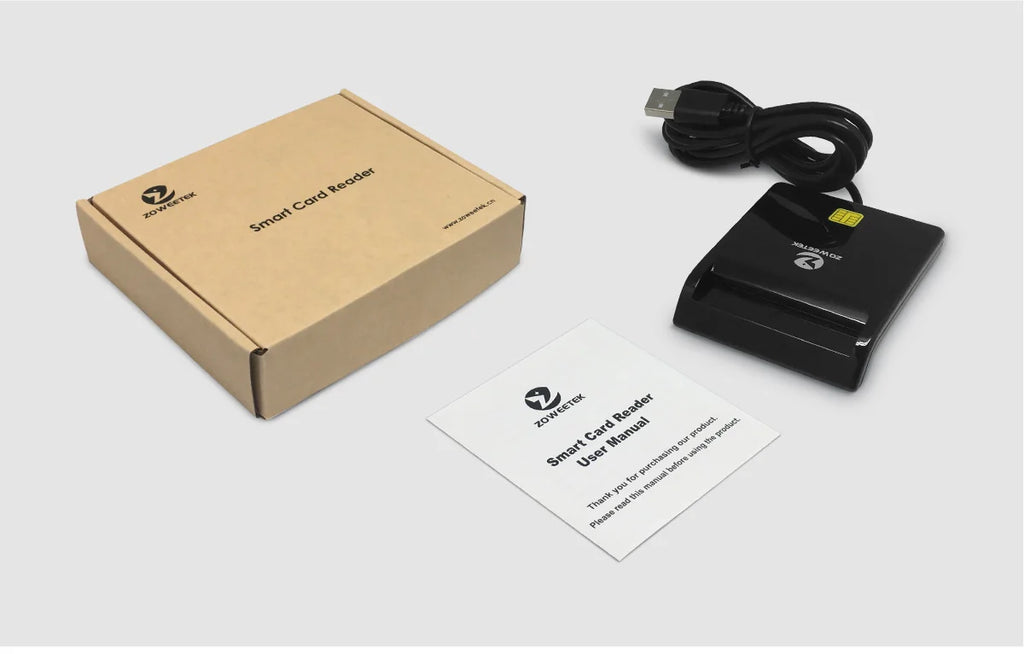 Black plastic smart card reader with USB cable, cardboard retail box, and user manual on a light grey background.