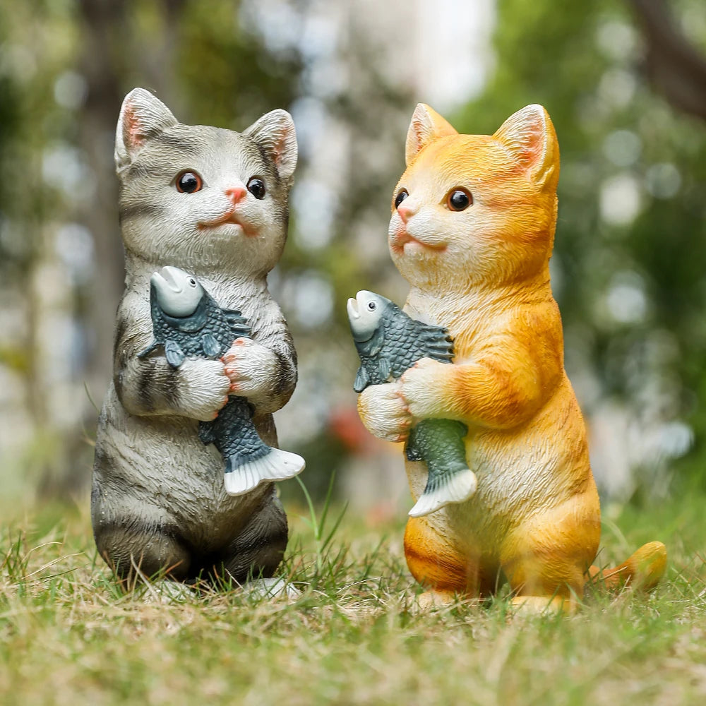 Two charming resin garden statues of an orange tabby and a grey tabby cat, both standing and holding fish.