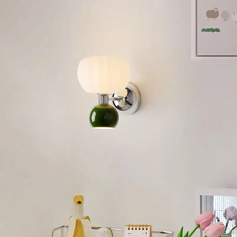 Modern wall lamp featuring a creamy white pumpkin-style shade above a glossy green sphere, mounted on chrome hardware.