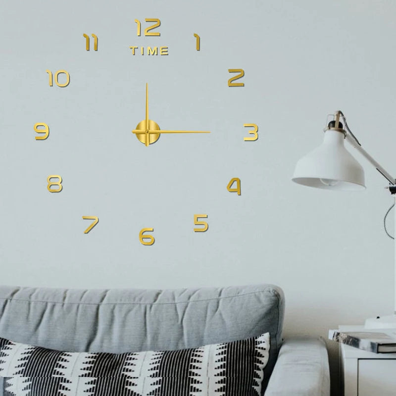 Large gold acrylic frameless wall clock with 3D numbers and central hands, mounted above a grey sofa.