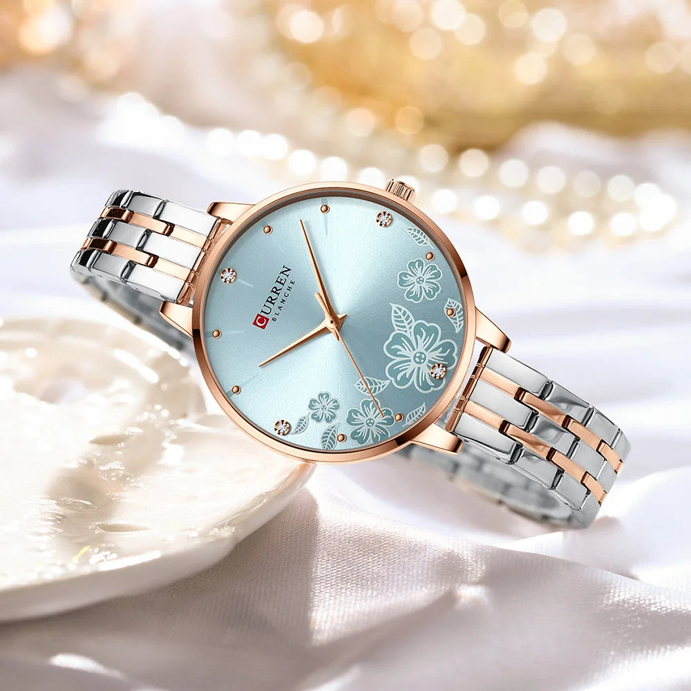 Curren quartz watch with a light blue dial, white floral motifs, and a two-tone rose gold and silver strap.