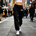 Woman wearing comfortable black joggers with an elasticated drawstring waist and cuffed hems, paired with white trainers.