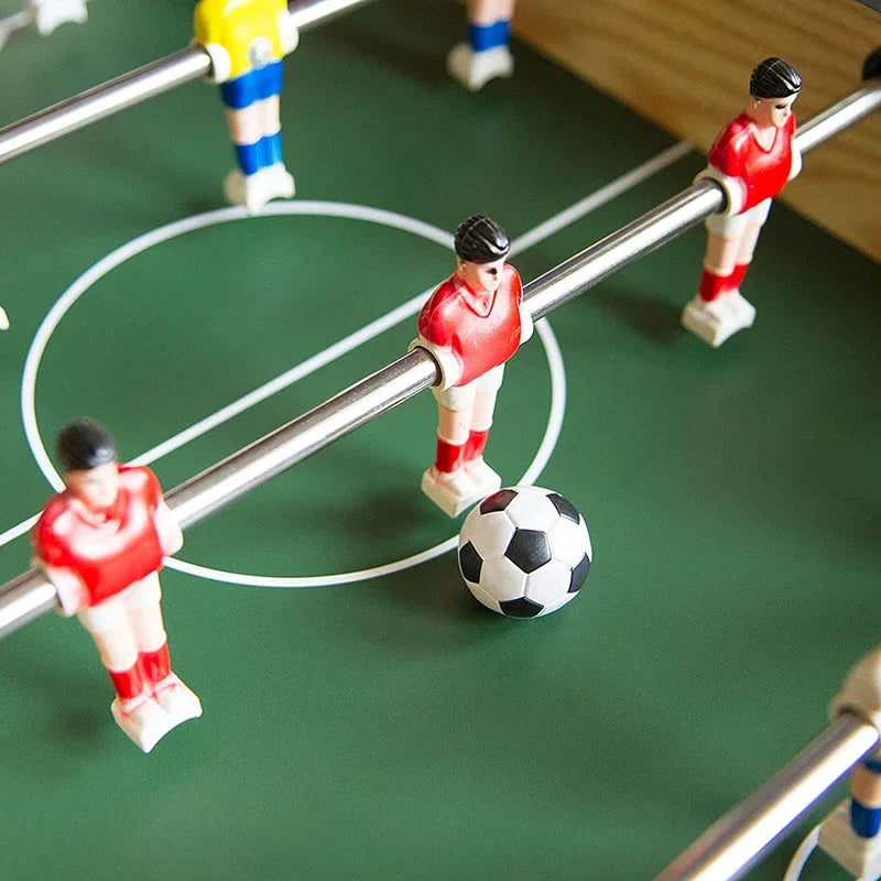 Close-up of a wooden foosball table with red and blue plastic players and a black-and-white football.
