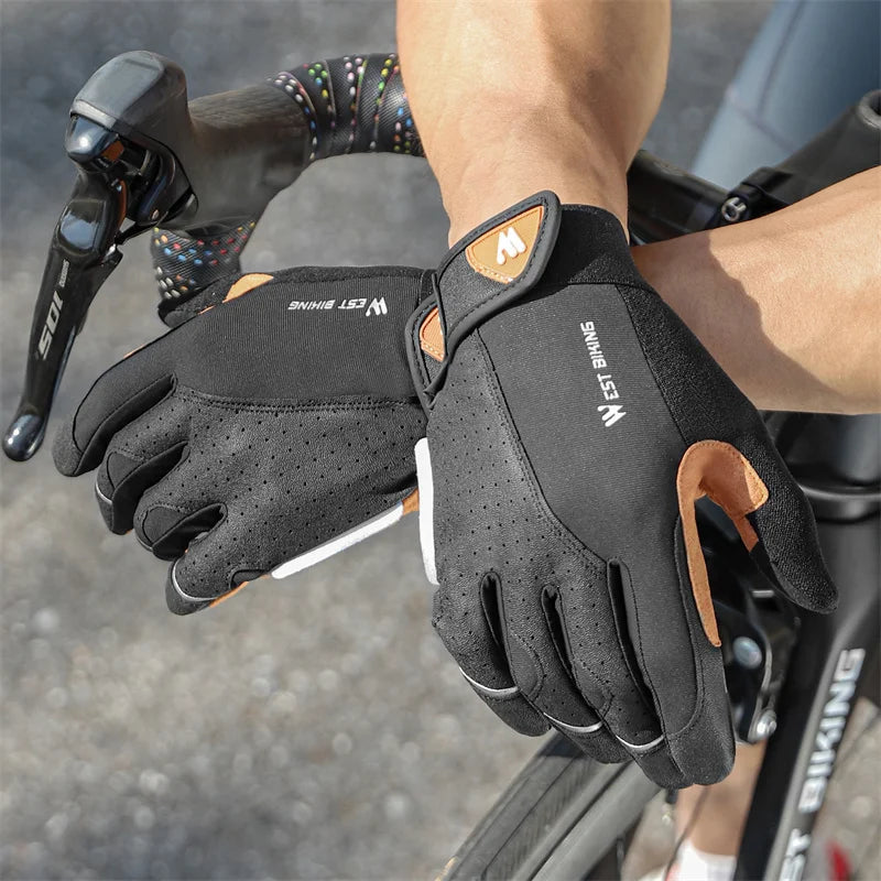 Black West Biking cycling gloves with tan accents, Velcro straps, and perforated material worn on bike handlebars.