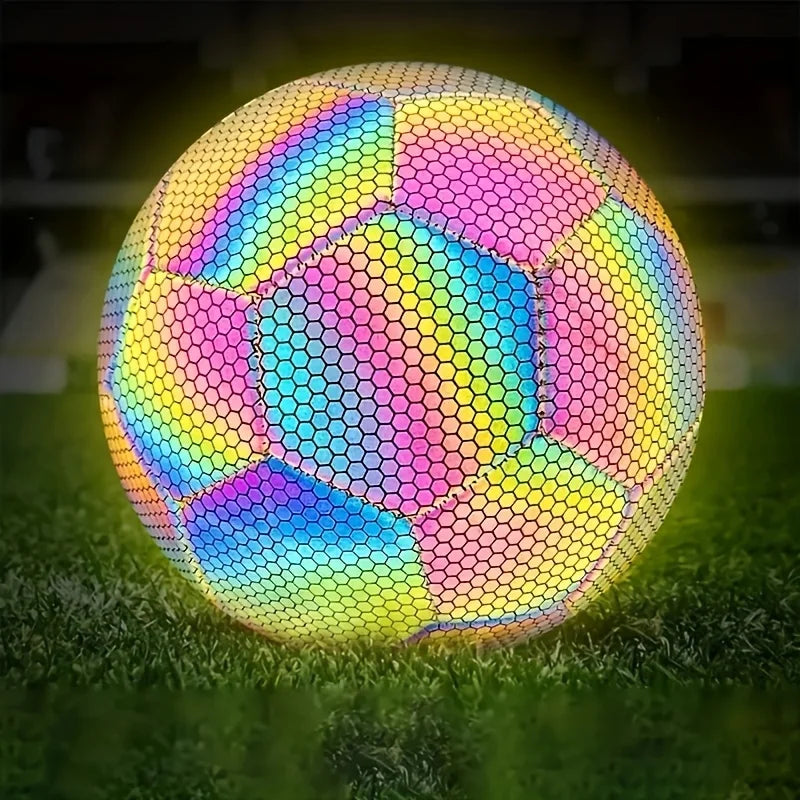 Reflective, multi-coloured football with a glowing honeycomb pattern, shown on a grass pitch.