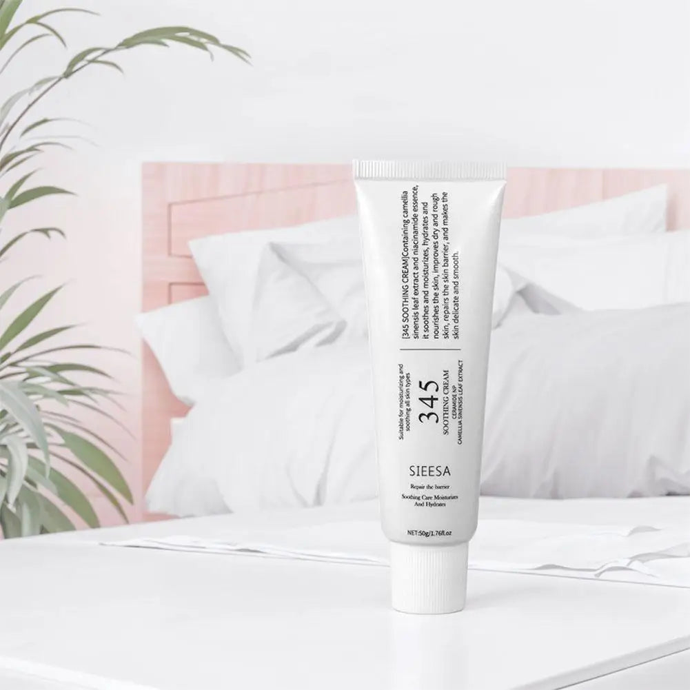 White tube of soothing face cream with camellia leaf extract and ceramide, shown on a white table in a bedroom.