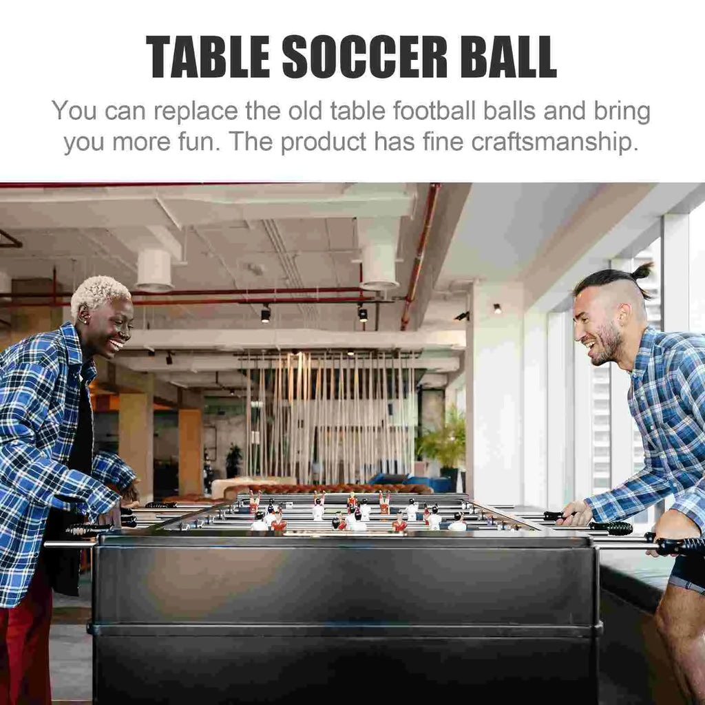 Two people playing a black foosball table with classic black and white replacement footballs.