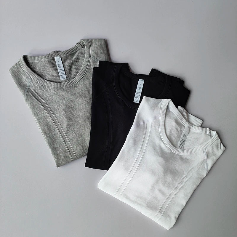Three seamless, short-sleeve sports t-shirts in grey, black, and white with ribbed texture detail.