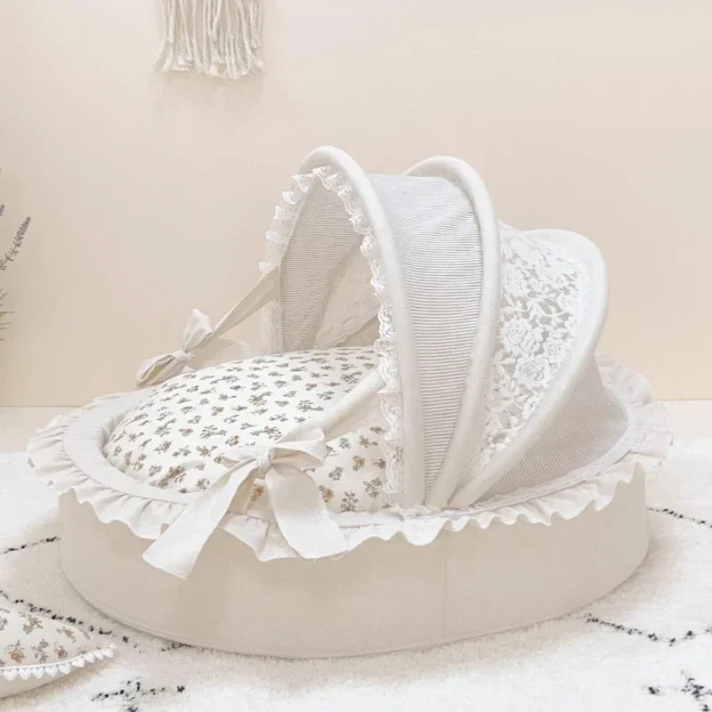White pet bed with a ruffled base, floral cushion, and lace canopy with bows.