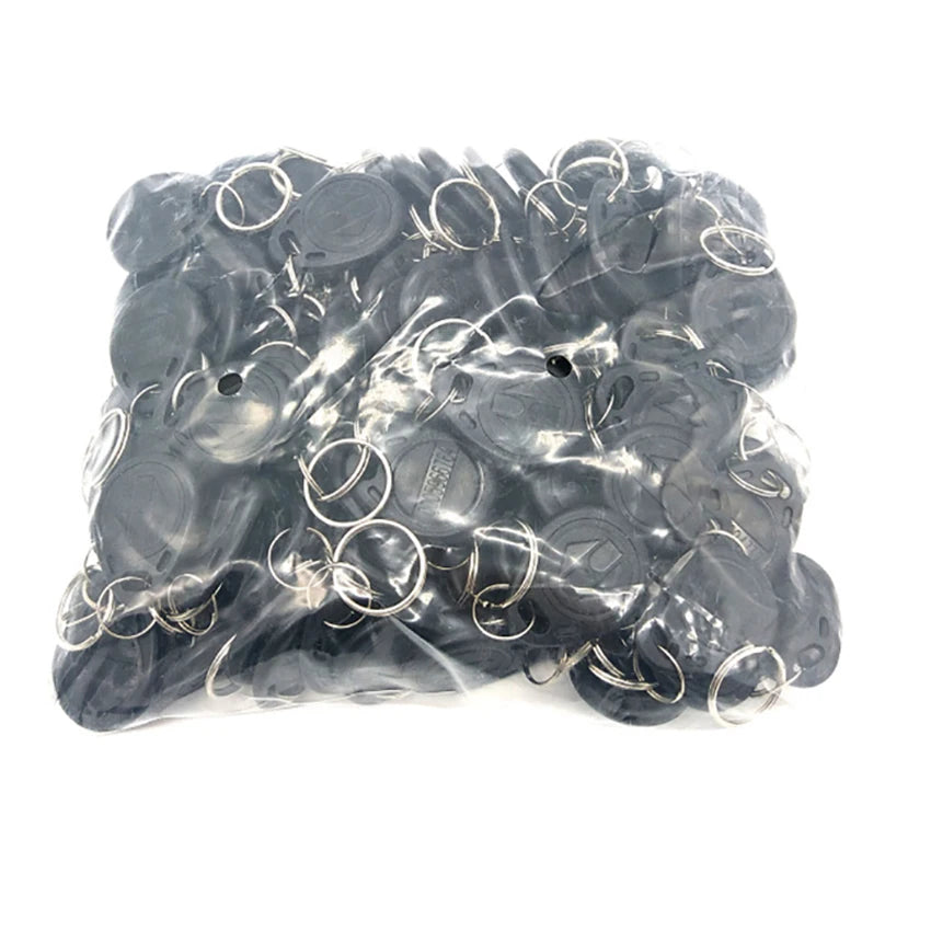 A bulk pack of round, black plastic RFID key fob tags, each with a metal split ring, in a clear plastic bag.