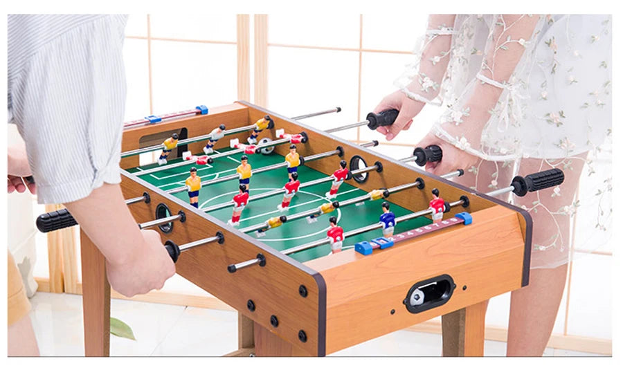 Wooden-finish foosball table with green pitch, sliding scorekeepers, and multi-coloured player figures.