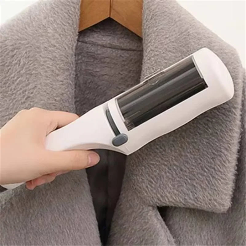 A white, handheld lint roller being used on a grey textured coat.