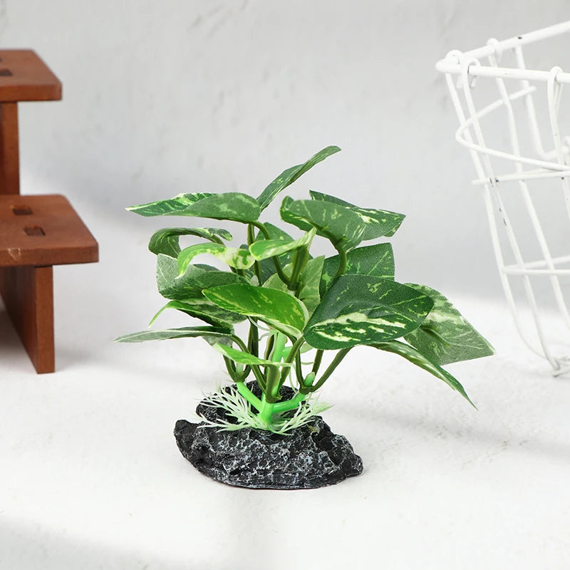 Artificial green variegated plant with sturdy stems rooted on a textured black stone base for aquarium use.
