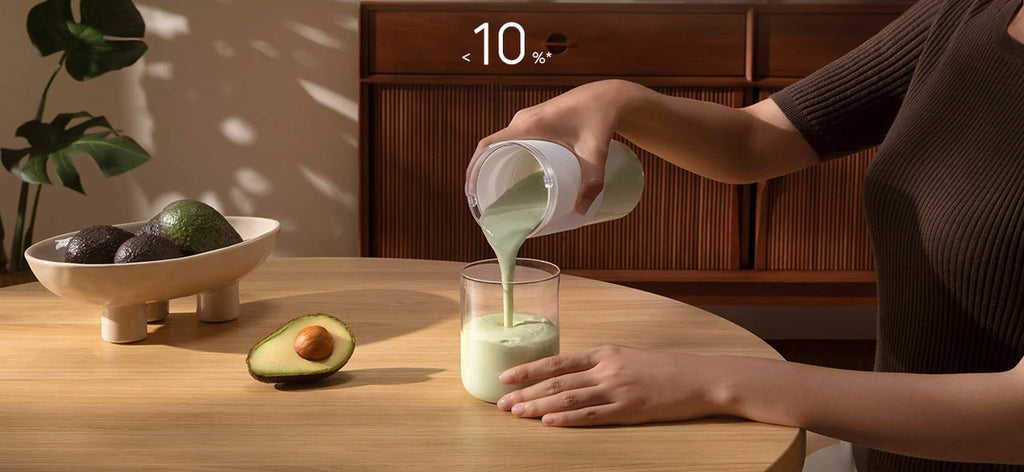 Person pouring a smooth green avocado drink from a sleek, minimalist white portable blender into a glass.