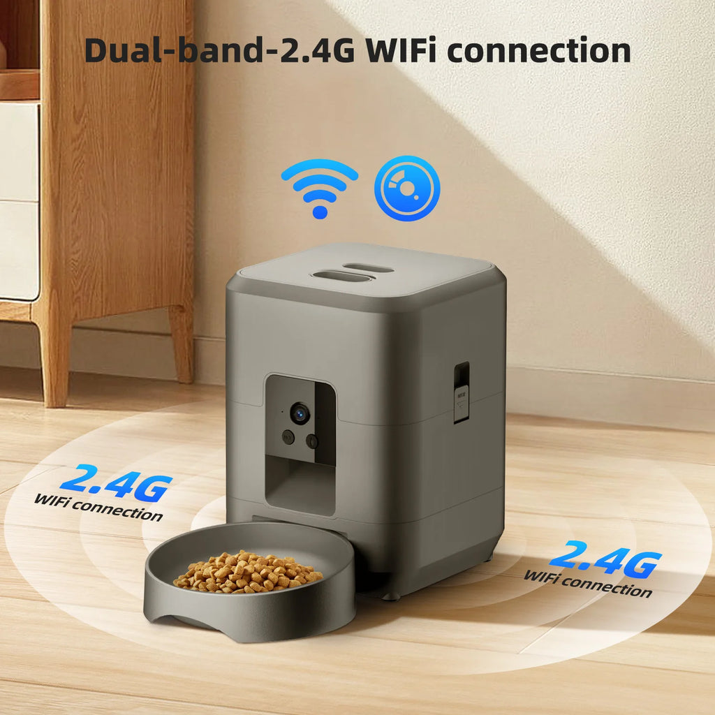 Modern grey square smart pet feeder with an integrated camera and a matching food bowl on a light wood floor.