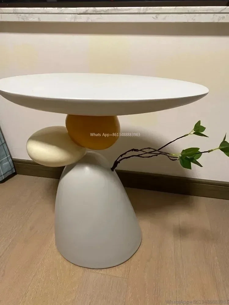 Minimalist cream-coloured side table with a unique sculptural base featuring stacked orb shapes and a decorative branch.