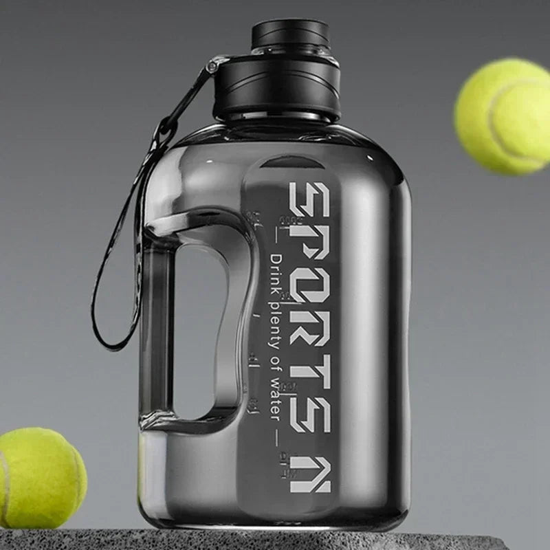 A large, translucent grey sports water bottle with a side handle and black lid, surrounded by two tennis balls.