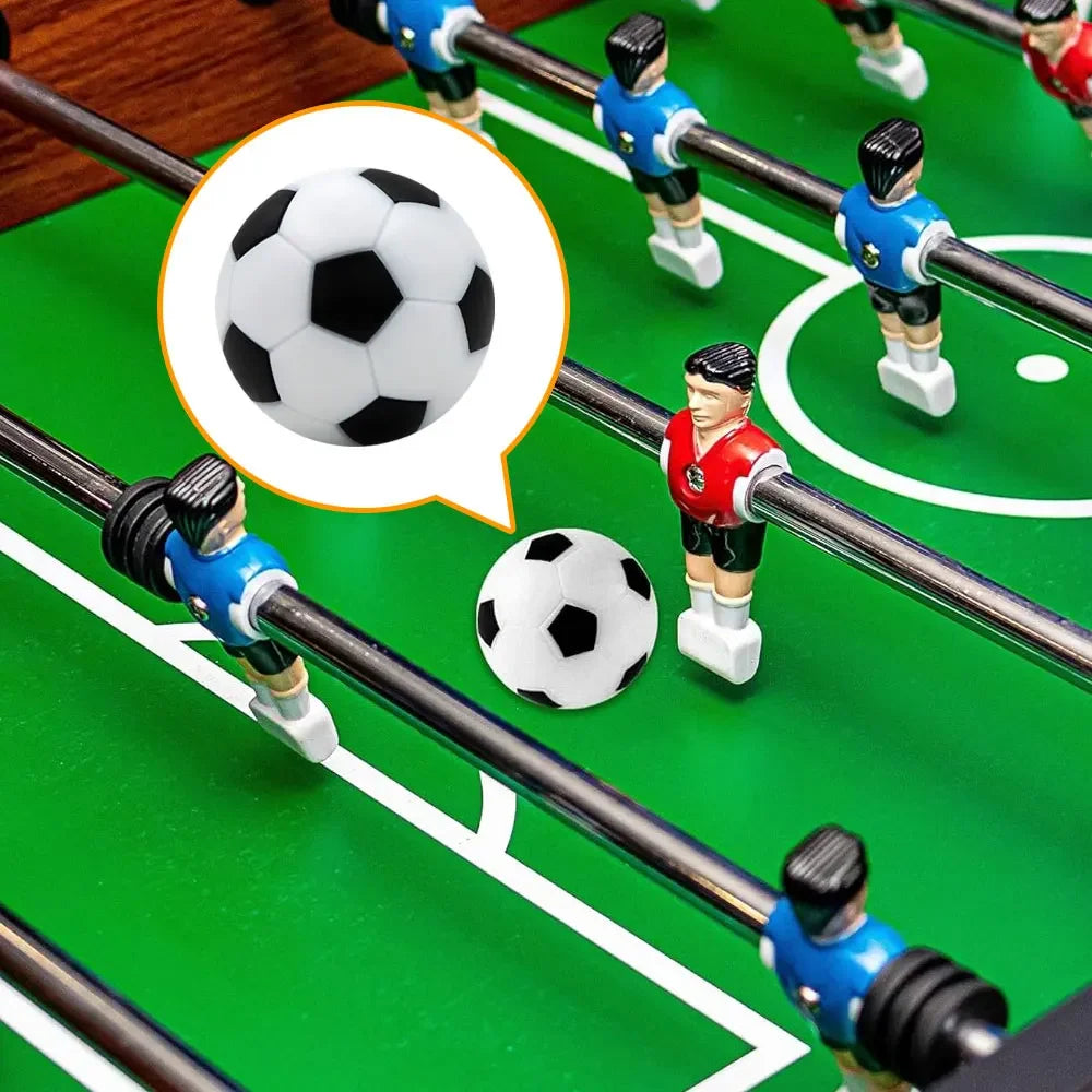 Classic black and white football for a table foosball game, shown in play on a green pitch with red and blue players.