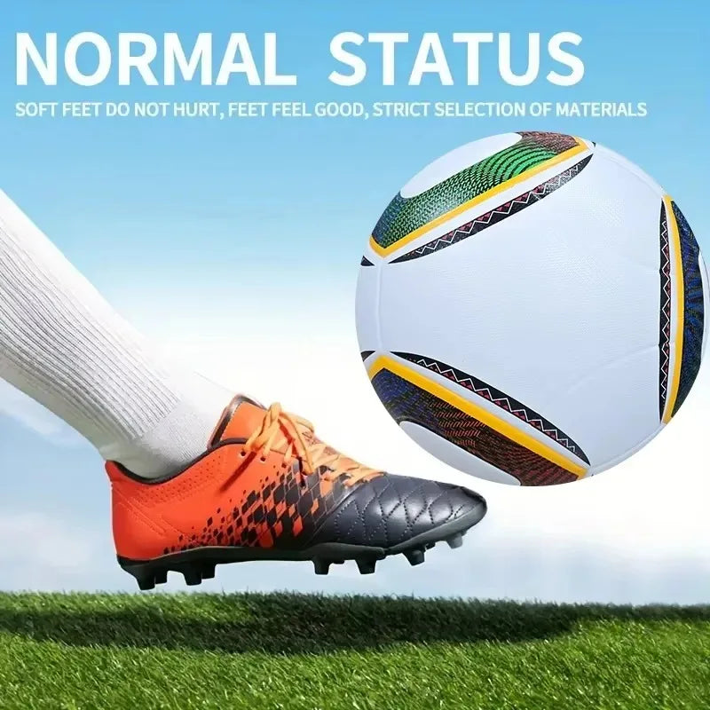 Orange and black football boots worn with white socks, kicking a white, multi-coloured patterned football on grass.