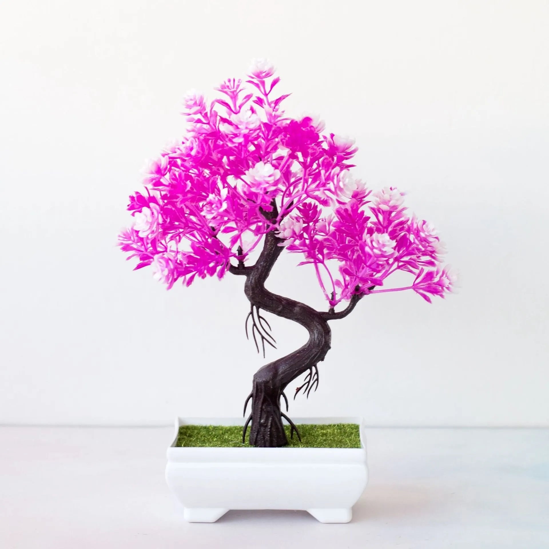 Artificial bonsai tree with vibrant pink and white leaves in a small rectangular white pot on a plain white background.
