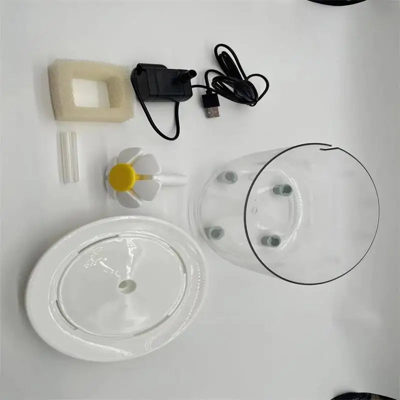 Pet water fountain kit including clear container, white circular base, USB pump, sponge filter, and flower nozzle.