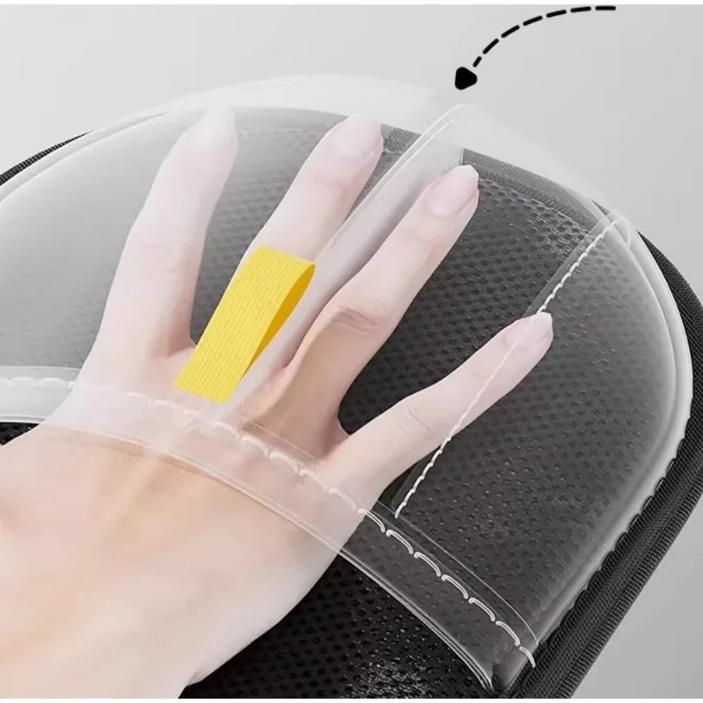 A hand wearing a transparent plastic mitt with a yellow strap, positioned over a black textured accessory case.