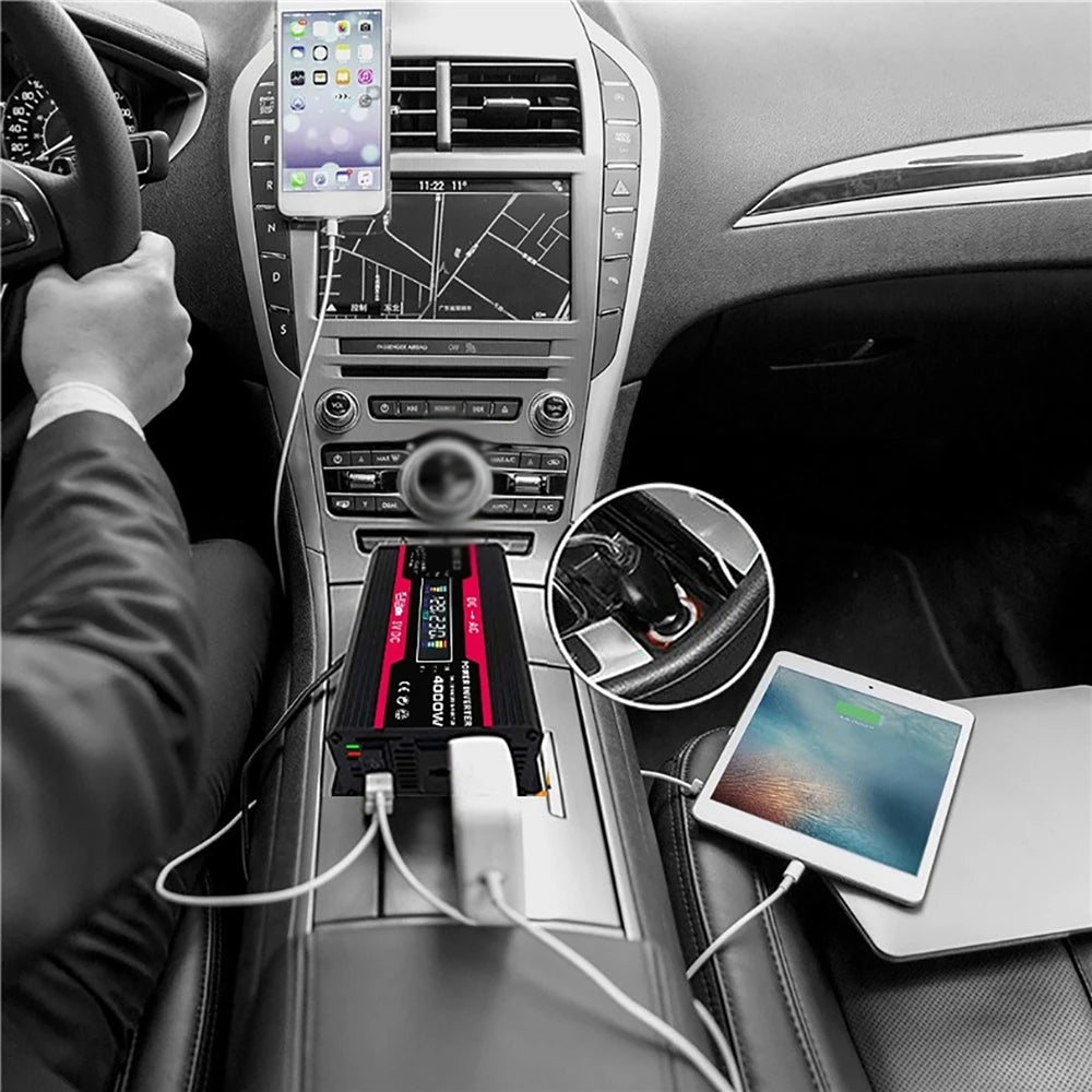 Black 4000W car power inverter with LCD display plugged into a car, charging a tablet and mobile phone.