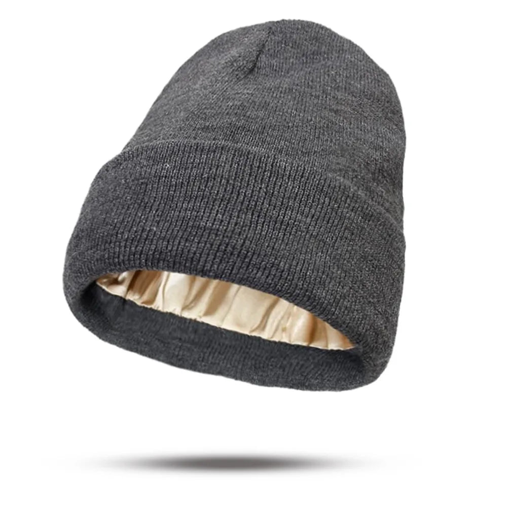 Charcoal grey knitted beanie hat with a smooth, champagne-coloured satin lining.