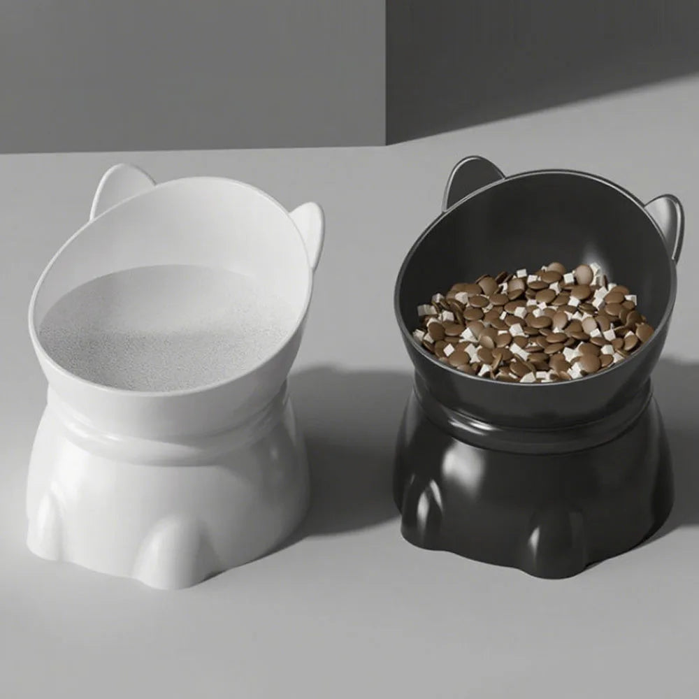 Two elevated pet bowls in white and black, shaped like cute cat heads with angled rims for ergonomic feeding.
