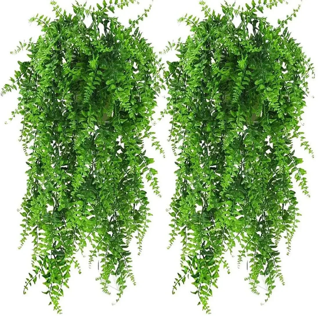 Two lush, vibrant green artificial Boston fern hanging bushes with textured, trailing fronds on a white background.