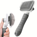 Grey and white self-cleaning pet slicker brush with a textured handle, shown with collected pet fur.