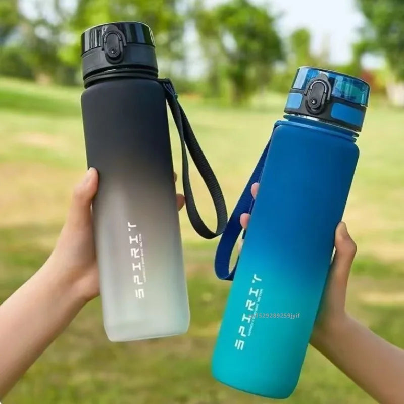 Two frosted ombre sports water bottles with carry straps and flip lids, held against a blurred garden background.